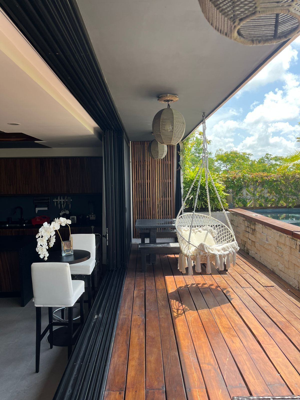 Terraza de madera del departamento, con columpio y la alberca al lado